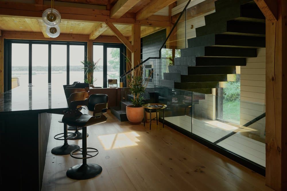 Great room with exposed timbers, open kitchen, floating stair, and river views