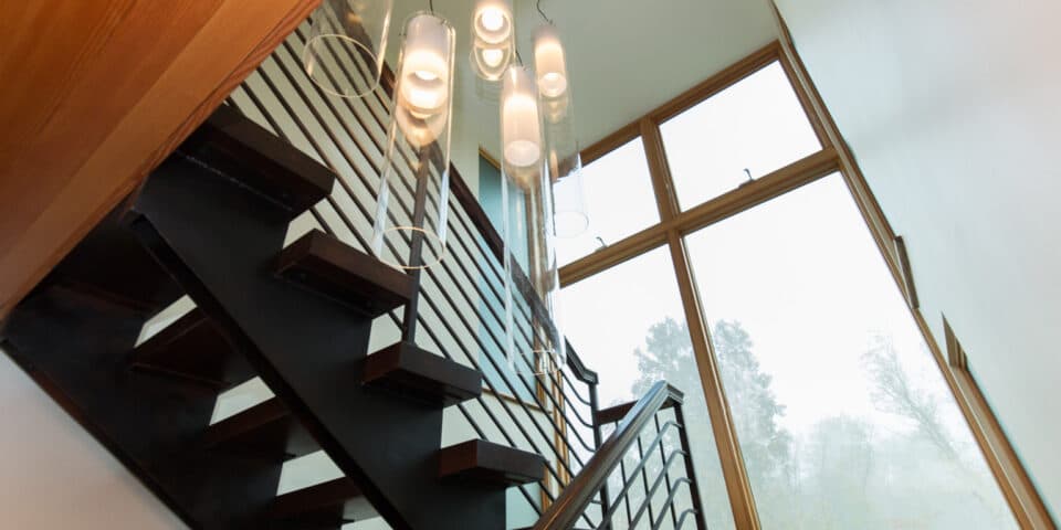 Open stair with cascading pendant lights and a two-story window wall
