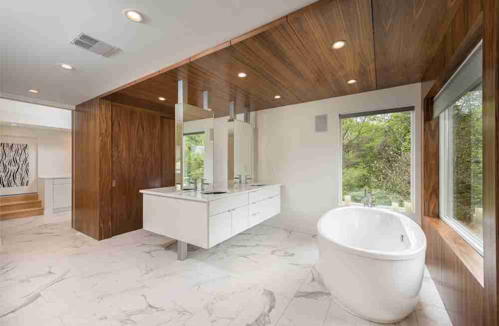 Primary bath with walnut ceiling, floating vanity, and freestanding tub