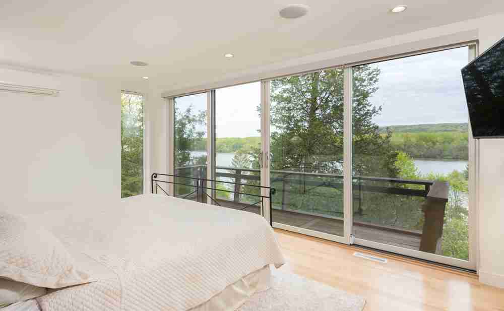 Bedroom with sliding glass wall opening to a balcony over the Hudson River